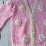 Hand-knitted, pink, floral patterned girl's cardigan.