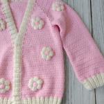 Hand-knitted, pink, floral patterned girl's cardigan.