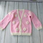 Hand-knitted, pink, floral patterned girl's cardigan.
