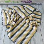 Hand-knitted baby blanket - embossed pattern in yellow, white and anthracite colors.