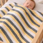 Hand-knitted baby blanket - embossed pattern in yellow, white and anthracite colors.